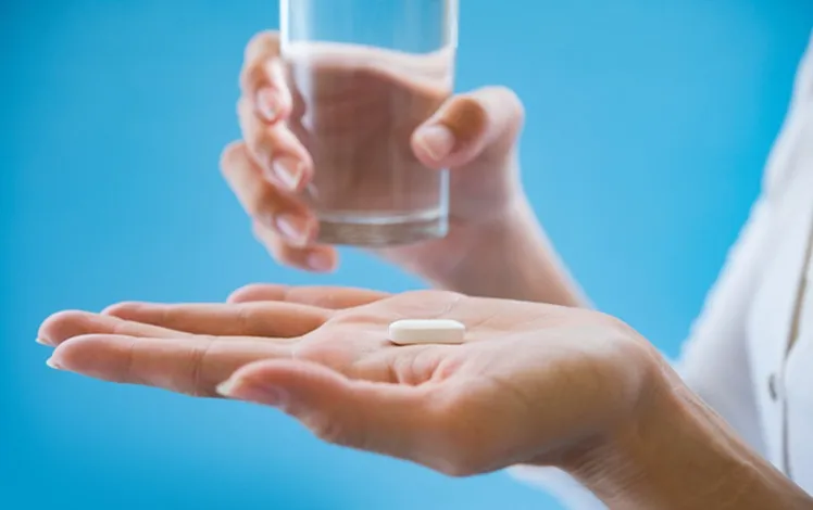 Vignette Actualité - Personne tenant un comprimé et un verre d'eau