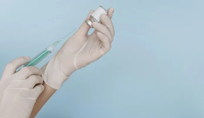 Vignette Actualité : Mains avec des gants tenant une seringue et une bouteille