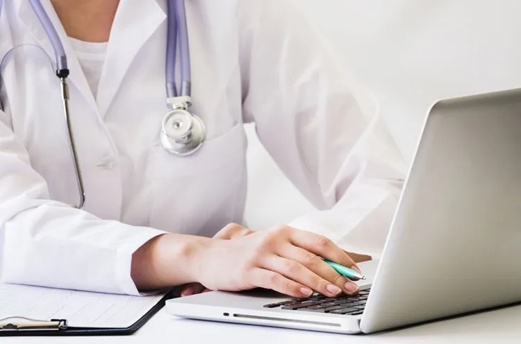 Vignette Actualité : Une femme médecin avec un stéthoscope autour du cou est assise devant son ordinateur portable sur son bureau