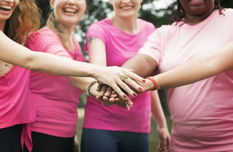 Vignette Actualité : Groupe de personnes vêtues de rose, les mains réunies en signe de solidarité à l’occasion d’Octobre rose.
