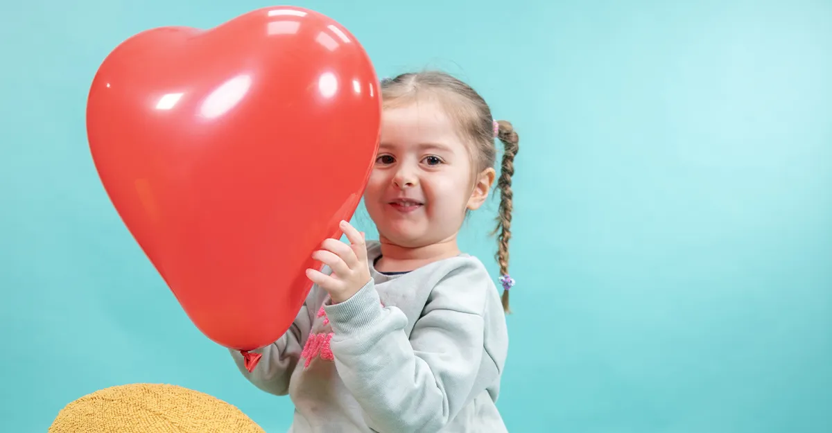 Victoire, ambassadrice du Téléthon 2024 tenant un ballon en forme de coeur dans un studio à l'AFM-Téléthon