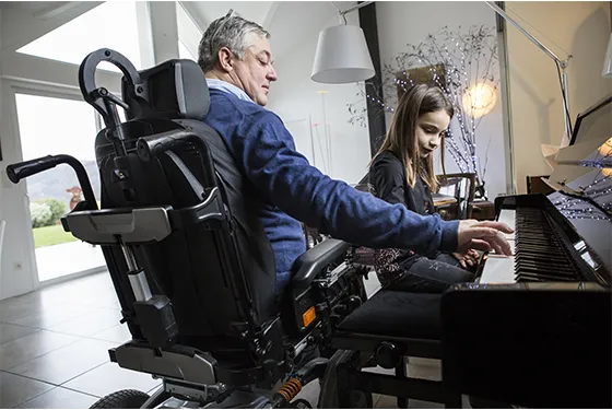 Un parent en situation de handicap aidant sa fille lors de leçons de piano