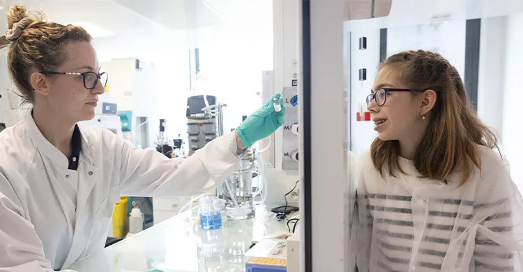 Une chercheuse de l'AFM-Téléthon montrant une fiole de thérapie à une jeune malade.