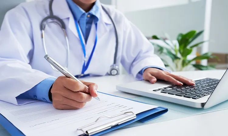 Vignette Actualité - Un médecin qui vérifie les informations sur son ordinateur avant de remplir son dossier médical