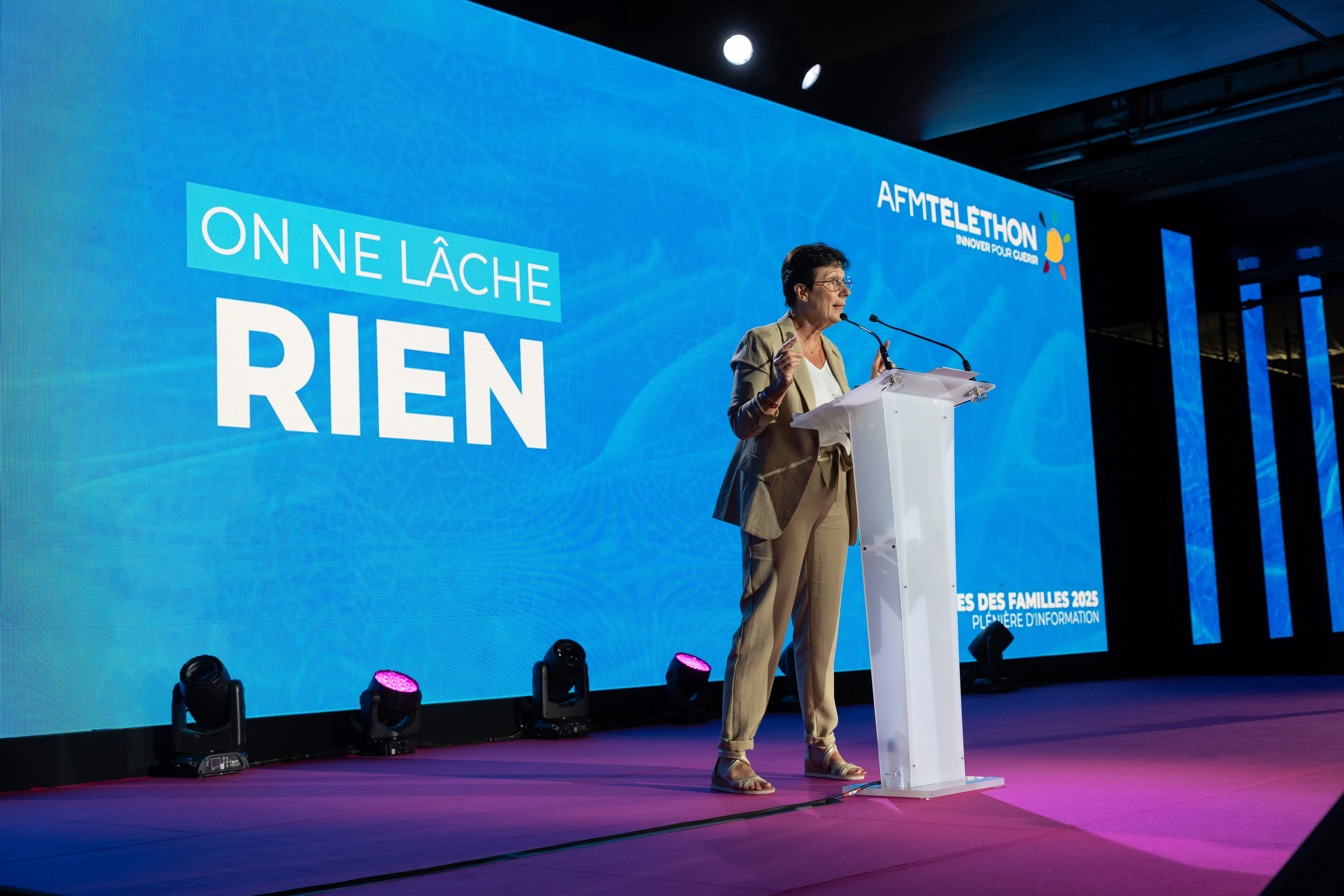 Laurence Tiennot-Herment, présidente de l’AFM-Téléthon, prononce un discours mobilisateur sur scène devant un grand écran affichant : “On ne lâche rien”. 