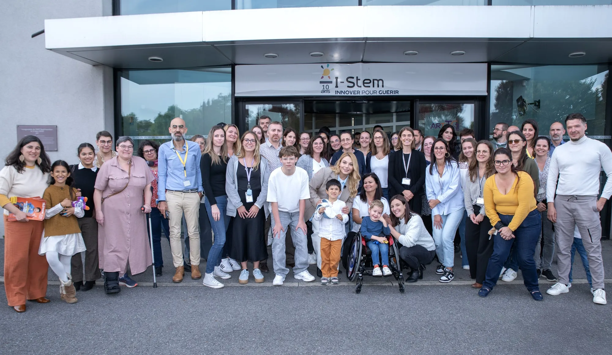 Photo de groupe devant I-Stem : chercheurs, salariés, familles et bénévoles réunis autour de Santa pour marquer sa visite à l'AFM-Téléthon