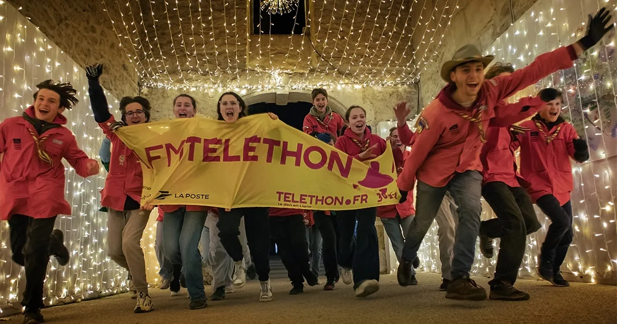 Animations du Téléthon : des bénévoles mobilisés sur le terrain portent une banderole AFM-Téléthon dans une ambiance festive, symbole de la mobilisation solidaire partout en France.