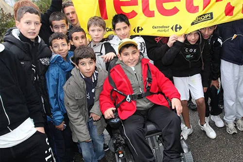 Téléthon 2010 : groupe d’adolescents mobilisés autour d’Edgar, atteint d’amyotrophie spinale, lors d’une tournée solidaire de 1 600 km pour sensibiliser des collégiens à travers la France