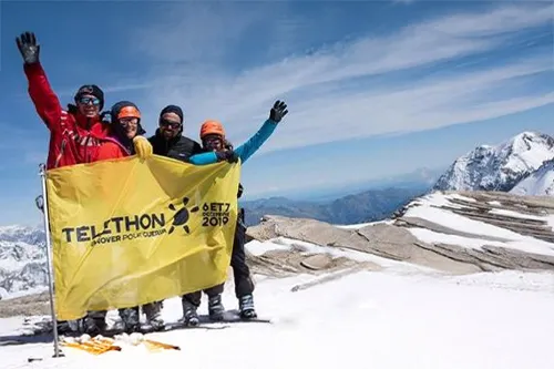 Téléthon 2019 : participants brandissent un drapeau Téléthon au sommet de l’Albaron à 3 637 mètres dans les Alpes, après une ascension solidaire