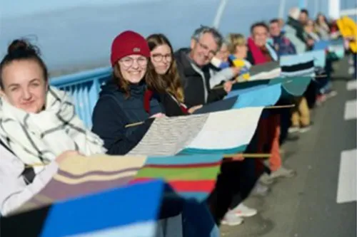 Téléthon 2021 : bénévoles déploient une écharpe géante tricotée collectivement pour recouvrir un pont à Saint-Nazaire, lors d’une mobilisation solidaire