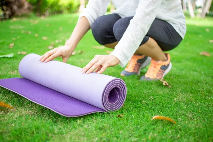Vignette actualité : Tapis d’exercice violet déroulé sur l’herbe par une personne se préparant à faire de l’activité physique en plein air