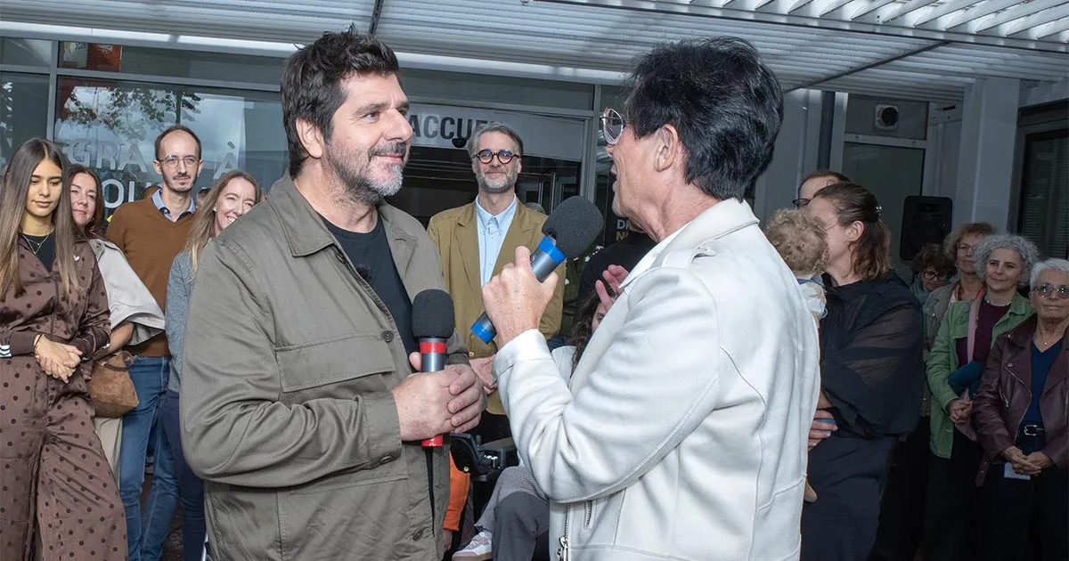 Patrick Fiori échange au micro avec Laurence Tiennot-Herment devant les salariés de l'AFM-Téléthon réunis pour sa visite.