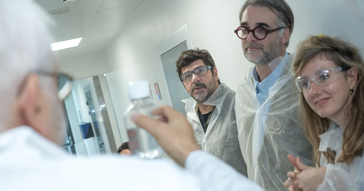 Manon et Julien, les parents de Jean ambassadeur du Téléthon 2026, observent une fiole dans le laboratoire de l'AFM-Téléthon, aux côtés de Patric Fiori