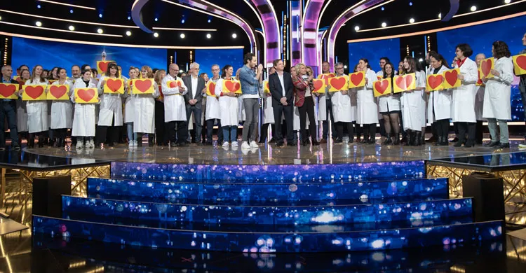 100 chercheurs sur le plateau du Téléthon 2023, tiennent des coeurs à la main