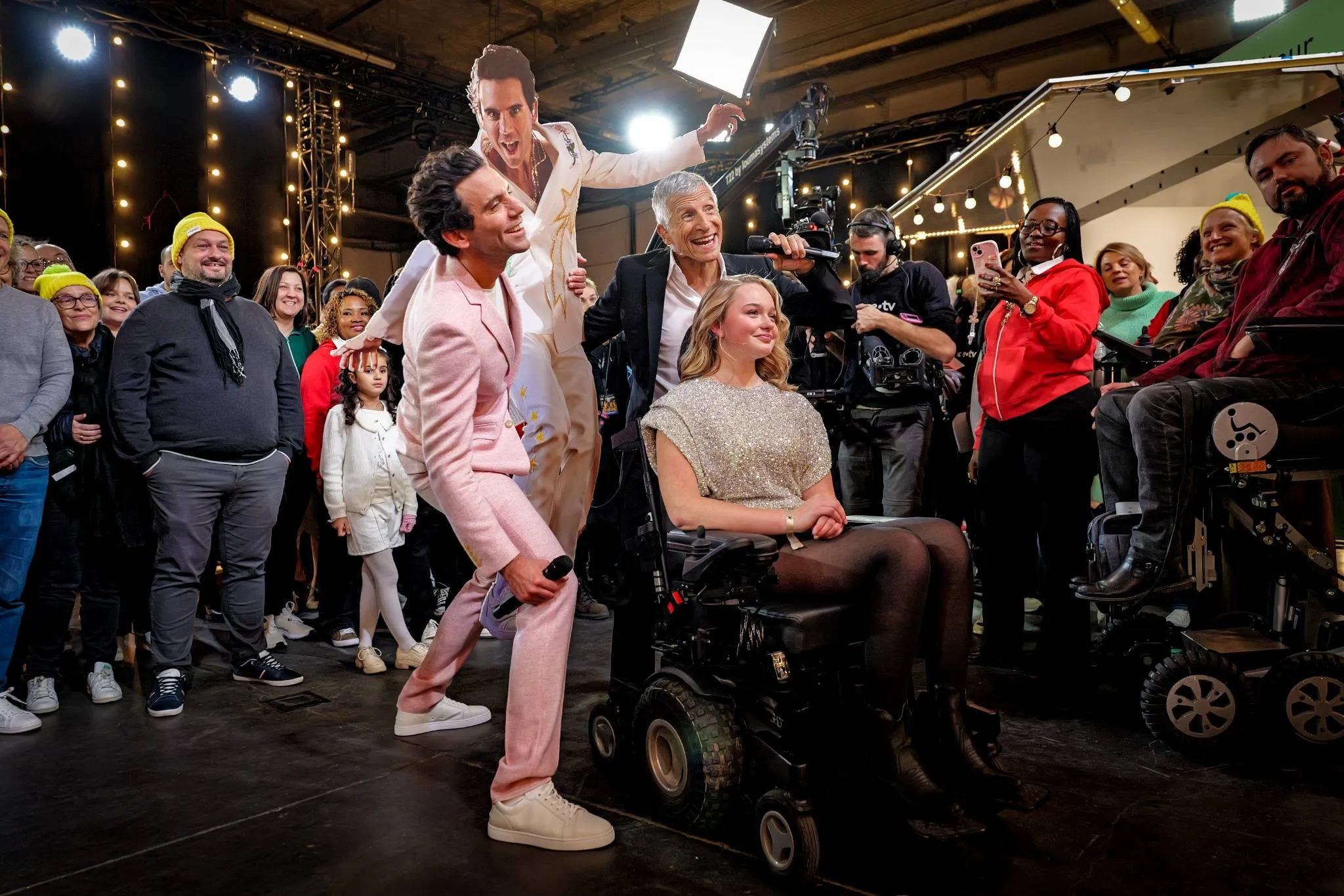 Mika, Nagui et Félicie, ambassadrice du Téléthon 2024, prennent la pose entourés des bénévoles.