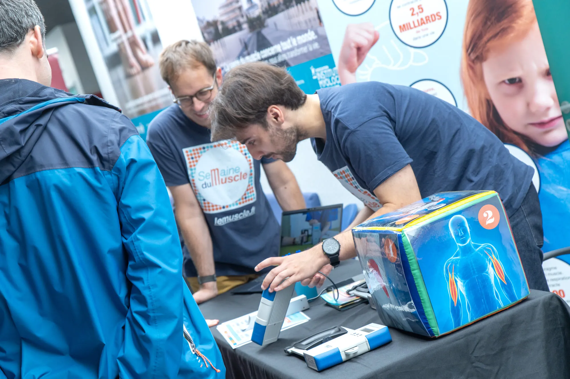 Des visiteurs manipulent un dispositif interactif sur le fonctionnement des muscles, guidés par des animateurs scientifiques bénévoles lors de la Semaine du Muscle.