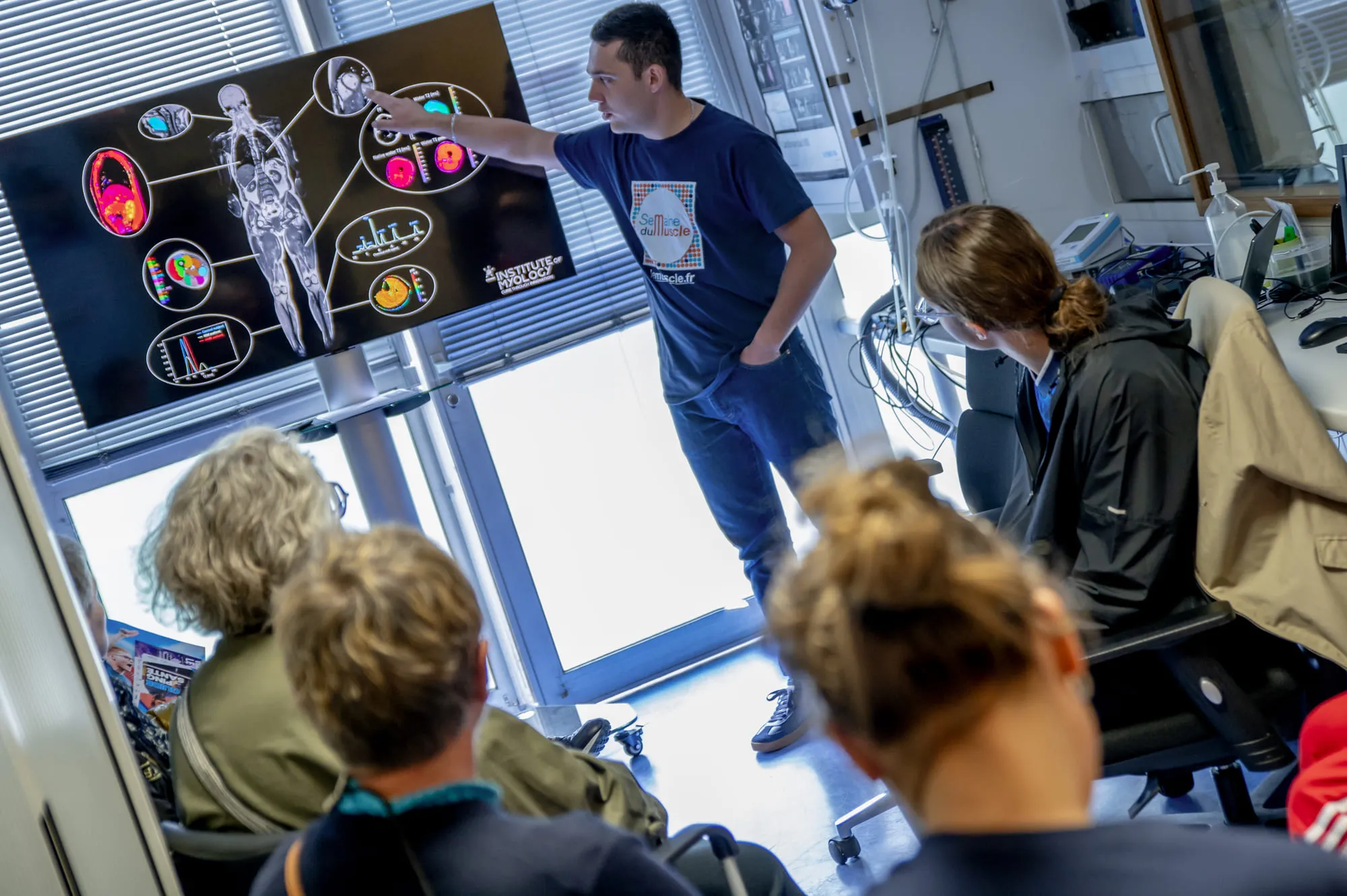 Un professionnel de santé présente les techniques d’imagerie médicale utilisées pour évaluer la masse et la qualité musculaire, devant un public attentif.