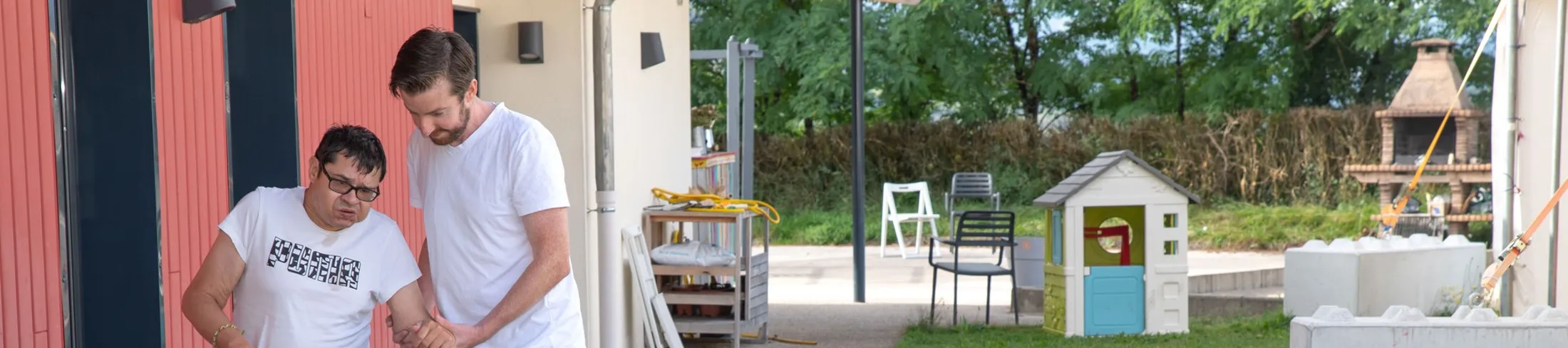 Un kiné aide une personne à s'installer dans son fauteuil roulant