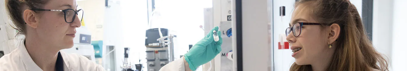 Une chercheuse de l'AFM-Téléthon montrant une fiole de thérapie développée dans l'un des laboratoires de l'association à une jeune malade