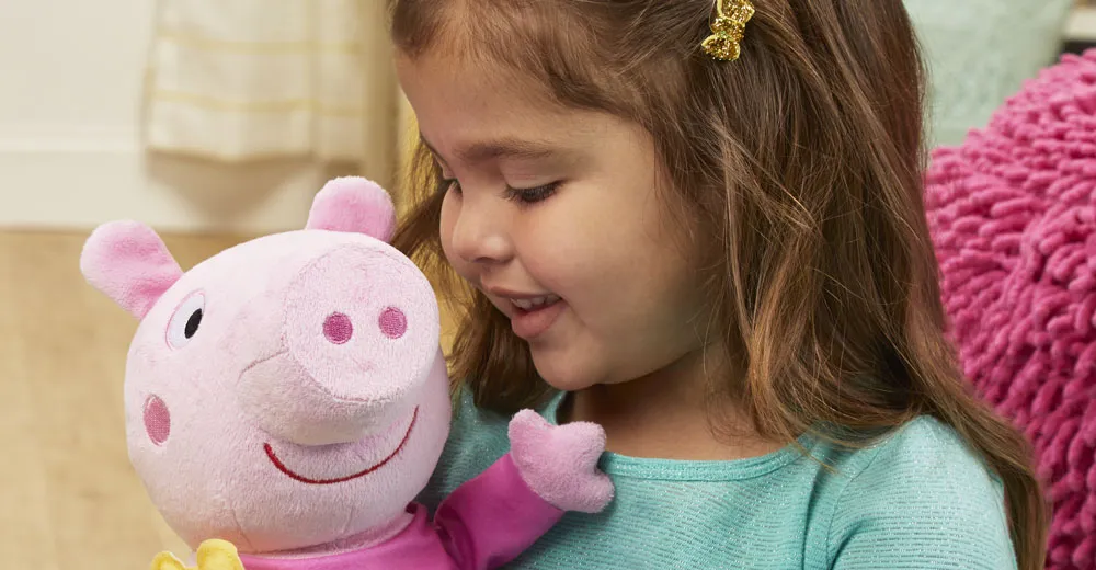 Une petite fille serre dans ses bras la peluche Peppa Pig