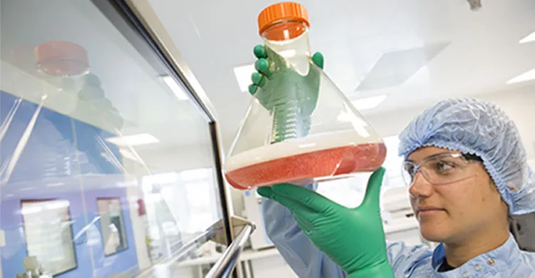 Une jeune femme dans un laboratoire tenant une fiole de produit de thérapie génique