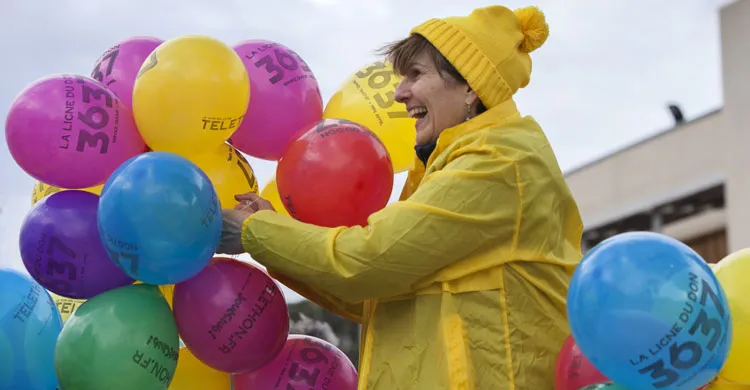 Une bénévole du Téléthon tenant des ballons 36 37