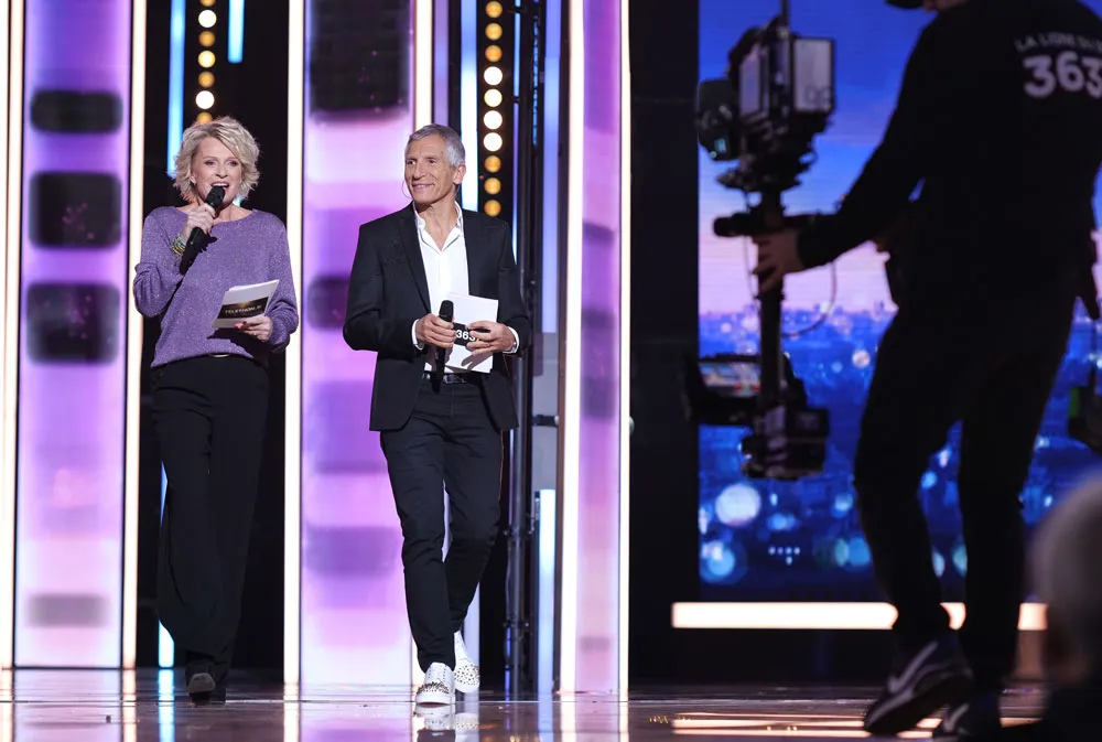 Nagui et Sophi Davant marchent côte à côte sur le plateau du Téléthon