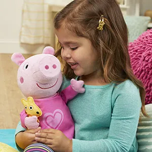 Une petite fille tient la peluche Peppa Pig dans ses bras