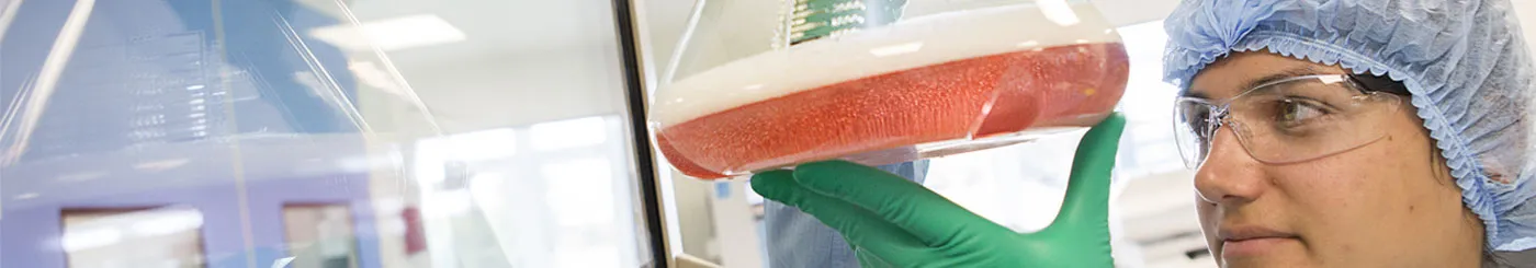 Une jeune femme dans un laboratoire tenant une fiole de produit de thérapie génique